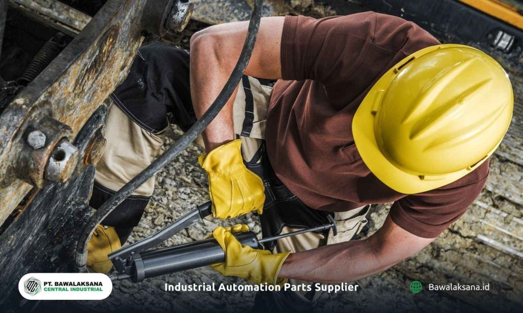 A technician operating a grease gun to lubricate moving parts in heavy machinery. An operator uses a pneumatically powered grease tool.